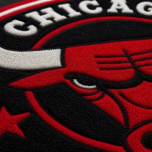 May include: Close-up of a circular patch featuring the word "CHICAGO" in white, above a red bull head. The patch has a black background with a red star and red outline. The design is embroidered.
