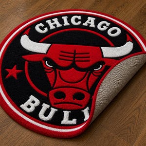 May include: A round rug featuring the Chicago Bulls logo. The rug has a red, black, and white color scheme, with the team name and bull head prominently displayed. The rug is made of a soft, textured material.