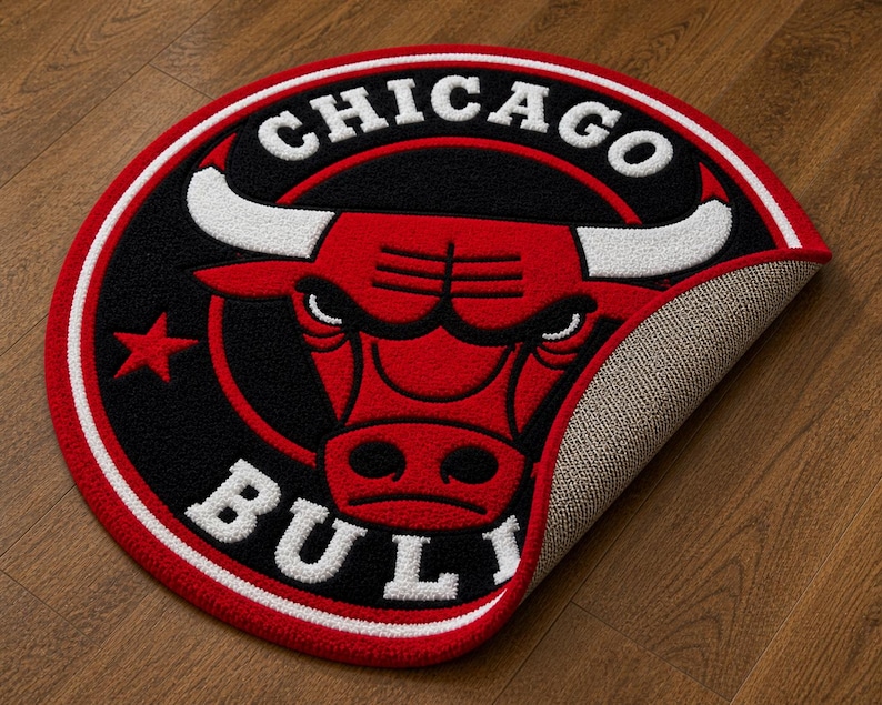 May include: A round rug featuring the Chicago Bulls logo. The rug has a red, black, and white color scheme, with the team name and bull head prominently displayed. The rug is made of a soft, textured material.