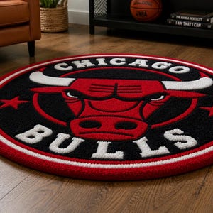 May include: A round rug featuring the Chicago Bulls logo. The rug has a black background with a red bull head and white lettering. The border is red and white. The rug is on a wooden floor.