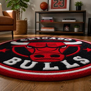 May include: A round rug featuring the Chicago Bulls logo. The rug has a black background with a red bull head and white lettering. The border is red and white. This sports-themed rug is suitable for a living room or bedroom.