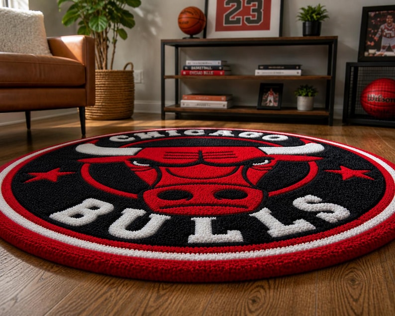 May include: A round rug featuring the Chicago Bulls logo. The rug has a black background with a red bull head and white lettering. The border is red and white. This sports-themed rug is suitable for a living room or bedroom.