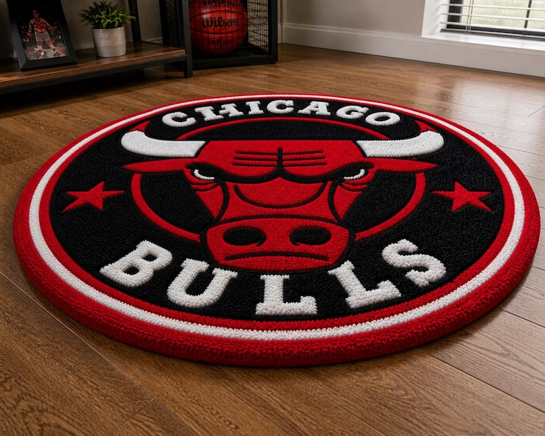 May include: A round rug featuring the Chicago Bulls logo. The rug has a black center with a red bull head and white lettering. A red and white border surrounds the logo. The rug is on a wooden floor.