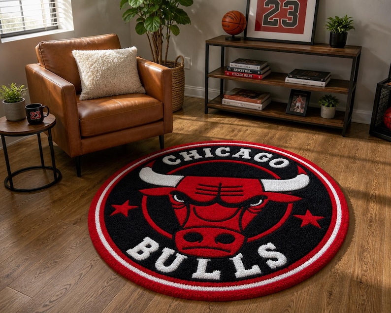 May include: A round rug featuring the Chicago Bulls logo in red, black, and white. The rug has a red border and the team name is prominently displayed. The rug is on a hardwood floor in a living room setting.