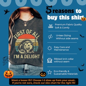 May include: A dark gray t-shirt featuring a vintage-style graphic of an opossum with the text "FIRST OF ALL I'M A DELIGHT" over a sunset background. The image includes a list of five product features and Halloween-themed icons like pumpkins and bats.