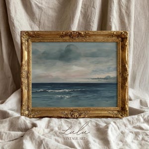 May include: An antique-style framed painting of the ocean under a cloudy sky. The artwork features shades of blue and gray, with a touch of pink in the sky. The ornate gold frame adds a vintage aesthetic. The text "Lulu Vintage Art" is at the bottom.