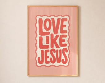 May include: A framed wall art print featuring the text LOVE LIKE JESUS in bold, red, rounded lettering. The words are centered within a cream-colored, scalloped-edge rectangular shape, all set against a solid light pink background.