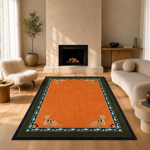 Puede incluir: Una alfombra rectangular naranja con un borde verde oscuro y azul marino. La alfombra presenta diseños decorativos en las esquinas en blanco, turquesa y dorado. La alfombra está en un salón.