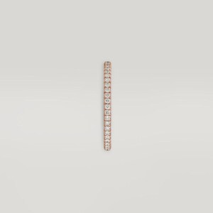 Puede incluir: Un anillo de oro rosa con una fila continua de peque&ntilde;as piedras preciosas transparentes. El anillo est&aacute; sobre un fondo neutro, resaltando el brillo de las piedras. El dise&ntilde;o es simple y elegante.