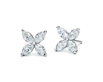 Op de afbeelding: Een paar oorstekers met een vierbladige bloemvorm. Elke oorbel heeft vier marquise-geslepen diamanten gezet in een zilverkleurig metaal. De oorbellen worden gepresenteerd tegen een witte achtergrond.
