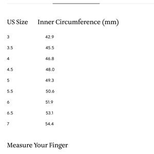 Puede incluir: Una tabla blanca con texto negro que detalla las tallas de anillos de EE. UU. y sus circunferencias internas correspondientes en mm. Las tallas van de la 3 a la 7. Instrucciones para medir un dedo.