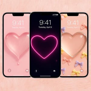 以下が含まれることがあります： ハートをテーマにした壁紙が表示された3台のスマートフォン。画面には9:41、4月9日火曜日と表示されています。1つはピンクのハート、もう1つはネオンピンクのハートの輪郭、3つ目はリボン付きのハートです。