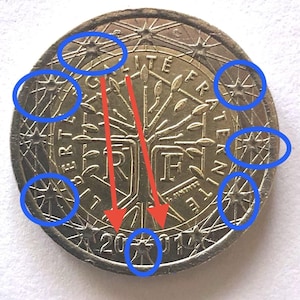 Può includere: Primo piano di una moneta in euro con l'anno 2014 visibile. La moneta presenta un disegno ad albero al centro, circondato dalle parole "LIBERTE EGALITE FRATERNITE". La moneta è di colore oro metallizzato.