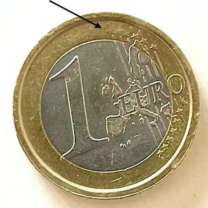 Può includere: Una moneta da un euro con un anello esterno dorato e un centro argentato. Il numero "1" è ben visibile, con la parola "EURO". Il design include una mappa dell'Europa.