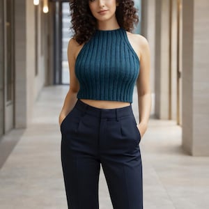 May include: Teal halter top with a ribbed texture, paired with navy blue high-waisted trousers. The top has a high neckline and is cropped. The trousers have a tailored fit with pockets. The outfit is suitable for casual or semi-formal occasions.