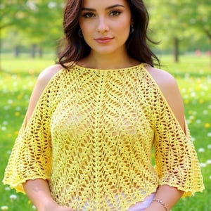 Op de afbeelding: Een gele gehaakte top met open schouders. De top heeft een gedetailleerd openwerkpatroon en driekwart mouwen. Het kledingstuk is gemaakt van een zacht, lichtgewicht garen, perfect voor warm weer. De achtergrond is een vage buitenscène.