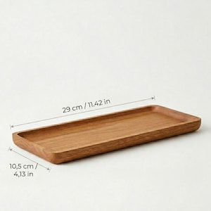 Pu&ograve; includere: Un vassoio rettangolare in legno, lungo 29 cm e largo 10,5 cm, con finitura a venatura naturale. Il vassoio ha un interno poco profondo e bordi arrotondati. Ideale per servire o esporre.