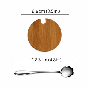 May include: A wooden, round bamboo lid with a notch, measuring 3.5 inches (8.9 cm) in diameter, and a stainless steel spoon with a flower-shaped bowl, 4.8 inches (12.3 cm) long. The spoon has a long, slender handle.