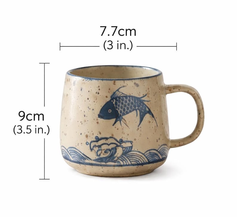 May include: A beige ceramic mug with a blue fish and wave design. The mug is 3.5 inches tall and 3 inches wide. It has a rounded shape and a large handle. The mug has a speckled finish.