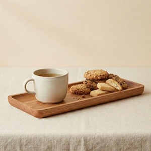 Pu&ograve; includere: Una tazza in ceramica beige chiaro con un manico curvo &egrave; su un vassoio di legno rettangolare. Il vassoio contiene diversi biscotti e pasticcini. I biscotti sono marroni dorati e i pasticcini beige chiaro.