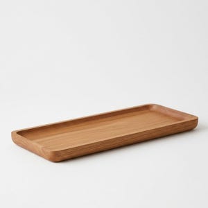 Pu&ograve; includere: Un vassoio rettangolare in legno con finitura marrone chiaro. Il vassoio ha un interno poco profondo e bordi arrotondati. La venatura del legno &egrave; visibile, aggiungendo consistenza. Progettato per servire o esporre.