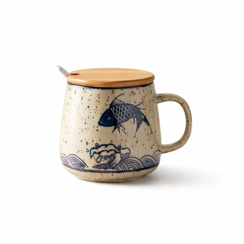 May include: Ceramic mug with a wooden lid and a small spoon. The mug features a speckled beige finish with blue fish and wave designs. The handle is curved, and the lid has a small notch for the spoon.