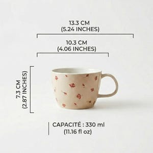 May include: A beige ceramic mug with a floral pattern of small red flowers. The mug is 2.87 inches tall, 5.24 inches wide, and 4.06 inches in diameter. It has a capacity of 11.16 fl oz.