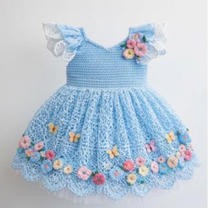 May include: A light blue crochet dress with a V-neck and a flared skirt. The dress is adorned with colorful crochet flowers and butterflies. The sleeves have white lace trim. The dress is designed for a child.
