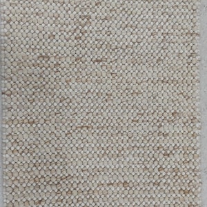 May include: A rectangular beige rug with a textured, nubby surface. The rug's design features a pattern of small, tightly packed, rounded elements, creating a tactile and visually interesting surface. The neutral colour palette makes it suitable for various interior styles.