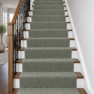Könnte beinhalten: Eine Treppe mit einem salbeigrünen Teppichläufer in strukturiertem Fischgrätenmuster. Die Stufen bestehen aus Holz mit weißen Setzstufen, ergänzt durch einen Holzhandlauf und schwarze Metallgeländerstäbe, die zu einem Treppenabsatz mit Wandbild führen.
