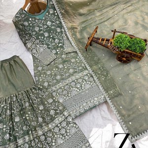 Pu&ograve; includere: Completo ricamato in tre pezzi verde salvia. Il set comprende una tunica a maniche lunghe, pantaloni a gamba larga e una sciarpa abbinata. La tunica e i pantaloni presentano ricami floreali intricati con dettagli argentati. La sciarpa &egrave; trasparente e leggera.