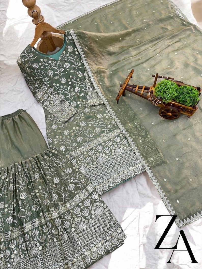 Pu&ograve; includere: Completo ricamato in tre pezzi verde salvia. Il set comprende una tunica a maniche lunghe, pantaloni a gamba larga e una sciarpa abbinata. La tunica e i pantaloni presentano ricami floreali intricati con dettagli argentati. La sciarpa &egrave; trasparente e leggera.