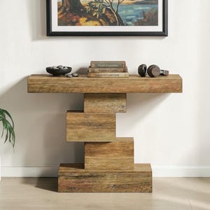 May include: A rustic wooden console table with a unique stacked design. The table has a rectangular top and a base made of stacked rectangular blocks. Books and a bowl are placed on the table's surface.