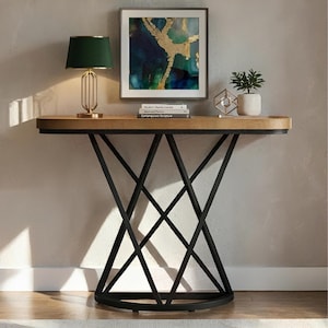 May include: A contemporary console table with a light wood top and black metal base. The table has a geometric design and is paired with a green lamp, artwork, and decorative items. The table is approximately 122 cm long.