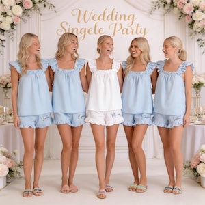 K&ouml;nnte beinhalten: F&uuml;nf Frauen in passenden Pyjama-Sets. Vier tragen hellblaue Sets mit R&uuml;schenoberteilen und Shorts, eine ein wei&szlig;es Set. Die Shorts sind mit Namen bestickt. Im Hintergrund steht der Text "Wedding Singele Party".