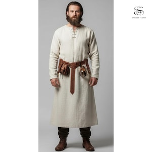 May include: A cream-colored tunic with long sleeves and a leather belt with pouches and a decorative glass vial. The tunic has a simple neckline with a tie closure. The belt is brown and has a decorative design.