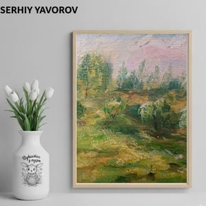 May include: An oil painting in a wooden frame depicts a landscape with green trees and grass under a pink and white sky. The artist's name, SERHIY YAVOROV, is at the top. A white vase with a bunny illustration and text holds white tulips.
