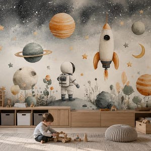 Op de afbeelding: Een muurschildering met een aquarelruimtescène met een astronaut die op een maan staat, een raket, verschillende planeten, sterren en een halve maan tegen een donkergrijze en crèmekleurige achtergrond met gestileerde planten.