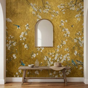 May include: A room interior featuring a gold-toned wall with a floral and bird design. A wooden bench holds a hat, bowl, and glass bottle. A gold-framed mirror hangs on the wall. The room has a warm, inviting atmosphere.