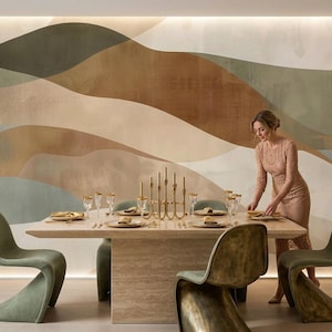 Puede incluir: Un conjunto de comedor con una mesa rectangular de piedra, cuatro sillas curvas de color verde salvia y un candelabro central dorado. La mesa está puesta con platos y vasos, frente a una pared con grandes formas abstractas y onduladas.