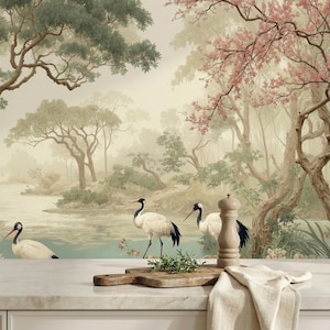 K&ouml;nnte beinhalten: Eine Tapete mit einer ruhigen Landschaft mit einem Fluss, B&auml;umen und Kranichen. Das Kunstwerk hat eine Vintage-&Auml;sthetik mit sanften Farben und einer nebligen Atmosph&auml;re. Ein Holzschneidebrett, Kr&auml;uter und ein Salzstreuer befinden sich im Vordergrund.