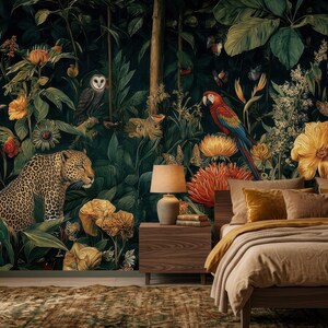 Pu&ograve; includere: Una camera da letto con carta da parati a tema giungla scura che raffigura un leopardo, un gufo e pappagalli colorati tra grandi fiori gialli e arancioni. Un comodino in legno con una lampada si trova accanto a un letto con cuscini marroni.