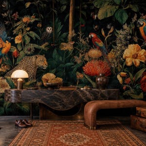 Pu&ograve; includere: Un murale con carta da parati dai toni scuri che presenta una fitta scena nella giungla con un leopardo, variopinti pappagalli, un gufo e grandi fiori tropicali. La scena include una console in marmo scuro, una panca in pelle marrone e due valigie vintage.
