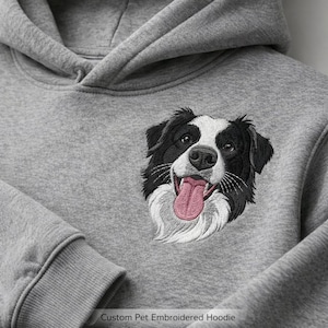 以下が含まれることがあります： カスタム刺繍された犬の顔が付いたグレーのパーカー。犬は白と黒の毛皮とピンクの舌をしています。「Custom Pet Embroidered Hoodie」というテキストが画像の下部にあります。