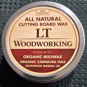 May include: A round metal tin of cutting board wax. The label reads "ALL NATURAL CUTTING BOARD WAX" with "LT WOODWORKING" below. Ingredients include organic beeswax and carnauba wax. The label also states "100% FOOD SAFE".