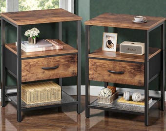 May include: Two matching nightstands with a rustic industrial design. Each has a dark brown wooden top, drawer, and shelf, supported by a black metal frame. The drawers have curved handles. One has a woven basket, the other has headphones.