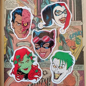 May include: Five die-cut stickers of DC Comics villains, including Two-Face, Harley Quinn, Catwoman, Poison Ivy, and The Joker. They are arranged on a vintage comic book page with speech bubbles and text.