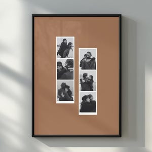May include: A framed wall art piece featuring a solid terracotta-coloured background with two vertical strips of black and white photo booth-style images. Each strip contains three distinct portraits of two people embracing in various poses.