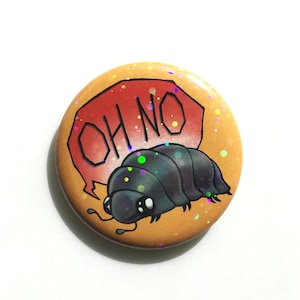 Könnte beinhalten: Ein runder, orangefarbener Button mit einer Cartoon-Rollassel-Illustration. Die Rollassel ist dunkelgrau mit großen Augen. Über der Rollassel befindet sich eine rote Sprechblase mit den Worten "OH NO" in Weiß. Der Button hat Glitzer.