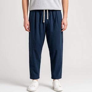 Puede incluir: Pantalones azul marino con cintura con cordón. Los pantalones tienen un corte relajado y un estilo casual. Los pantalones se combinan con zapatillas blancas. Los pantalones están hechos de una tela suave y ligera.